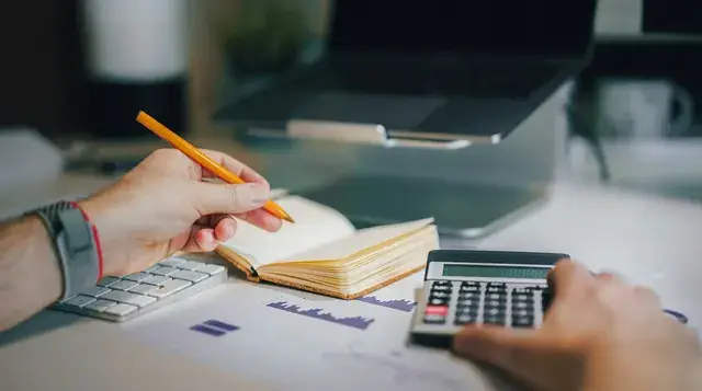 Planning a marketing budget with a calculator and notebook
